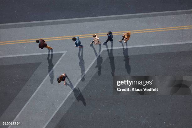 businesspeople walking in line on road, painted on asphalt, one person walking off in different direction - initiative photos et images de collection