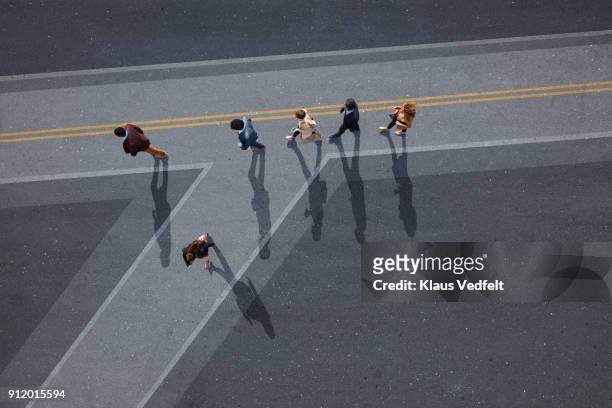 businesspeople walking in line on road, painted on asphalt, one person walking off in different direction - self doubt ストックフォトと画像