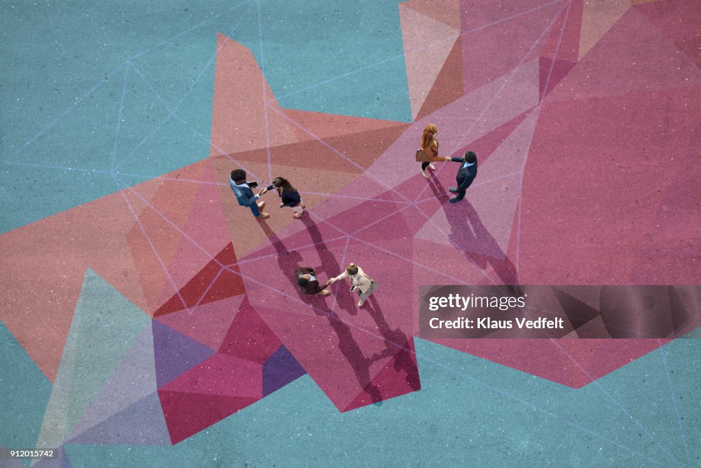 Businesspeople making handshakes, while standing on painted pattern on asphalt