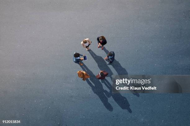 group of businesspeople standing in a circle on painted asphalt - call conference stock-fotos und bilder
