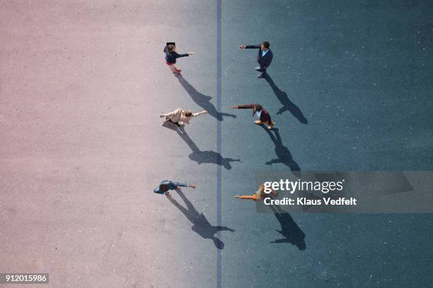 businesspeople stretching towards each other, on painted asphalt - disturbios fotografías e imágenes de stock