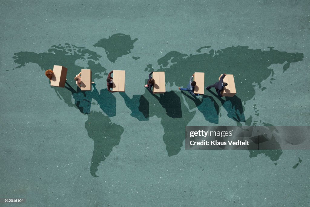 Businesspeople walking across painted world map, carrying moving boxes