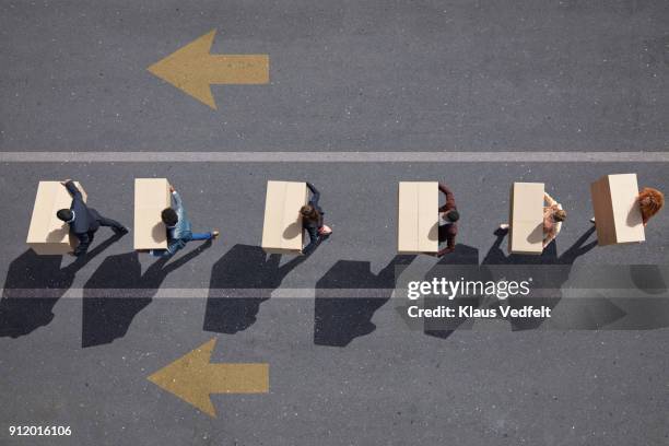 businesspeople walking in lane with painted arrows, carrying moving boxes - unemployed stockfoto's en -beelden