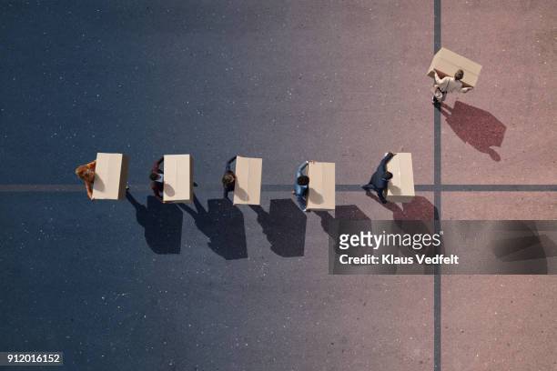 businesspeople with moving boxes walking in line. one person turning left, on painted asphalt - rotation concept stock pictures, royalty-free photos & images
