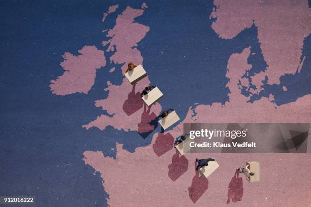 businesspeople carrying moving boxes, while walking out of great britain,on painted north european map on asphalt - downsizing 2017 film stock-fotos und bilder