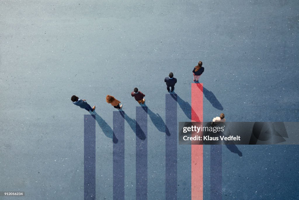 Businesspeople standing on painted bar chart graph on asphalt