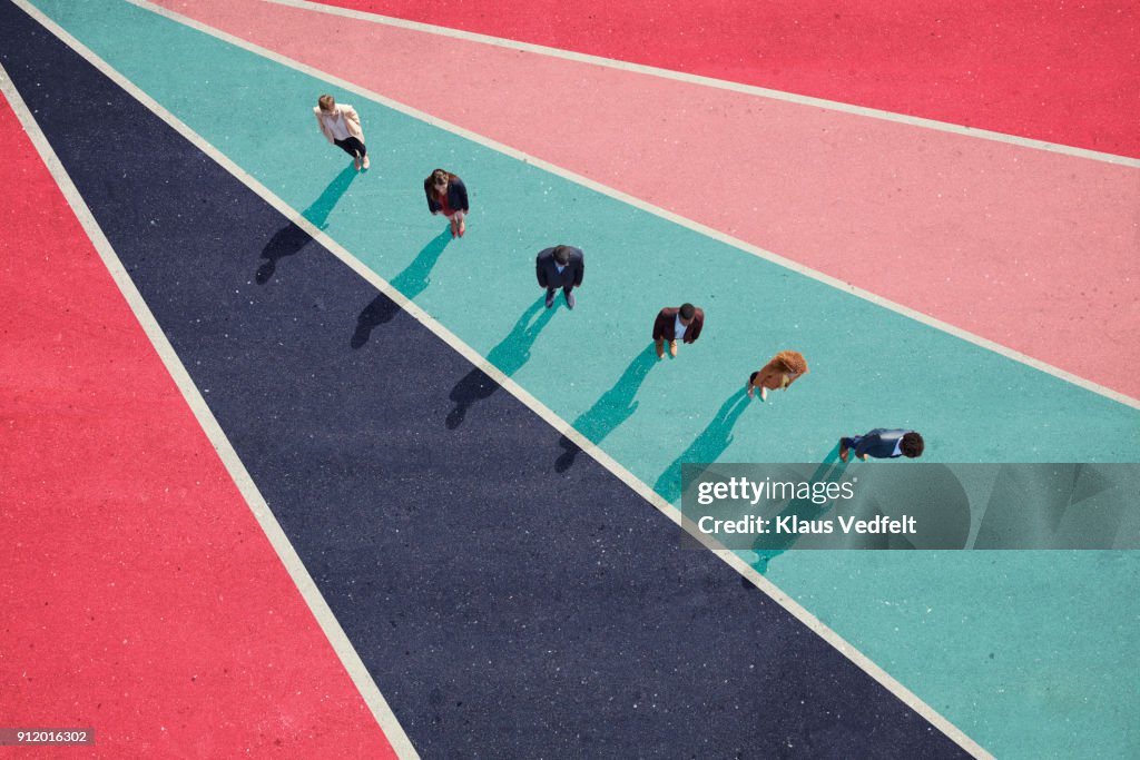Businesspeople standing in line on bright coloured asphalt