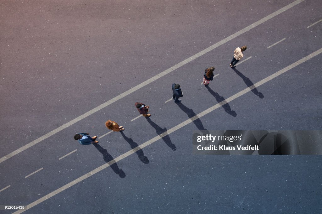 Businesspeople standing in line across road painted on asphalt