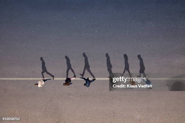 businesspeople walking across painted line on asphalt - shadow 個照片及圖片檔