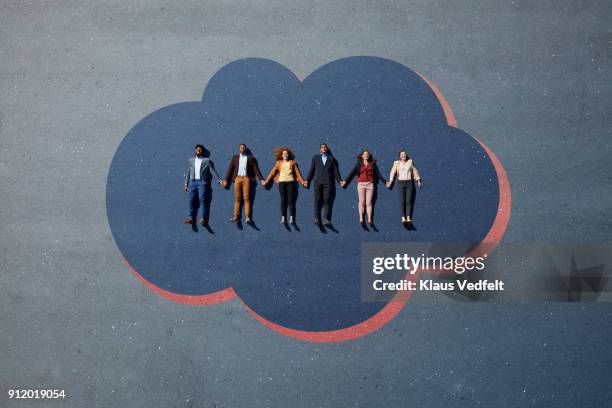businesspeople lying down and holding hands on cloud, painted on asphalt - estar-en-las-nubes fotografías e imágenes de stock