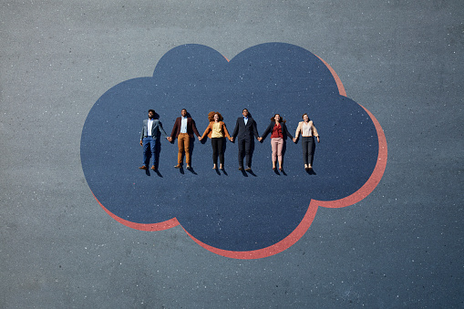Businesspeople lying down and holding hands on cloud, painted on asphalt