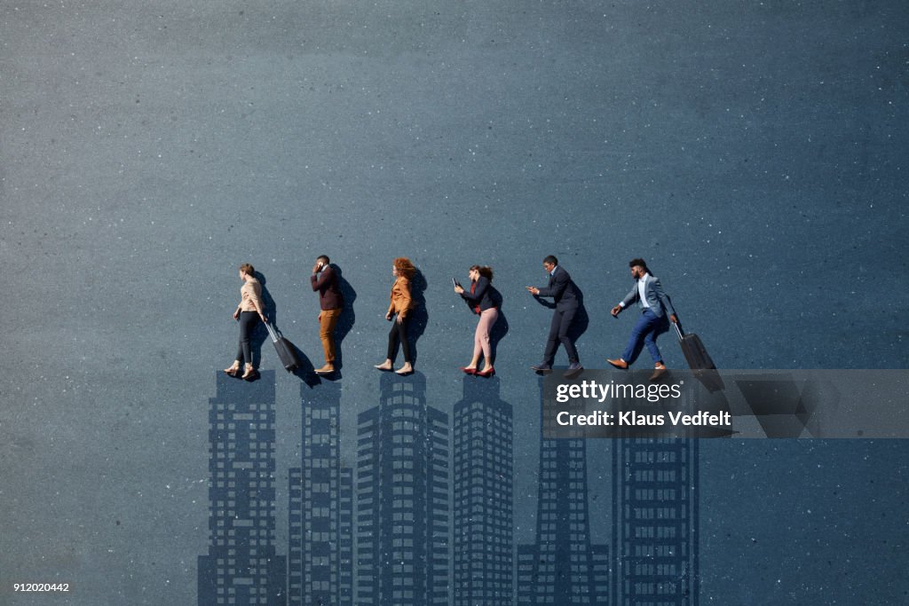 Businesspeople laying in line, with suitcases and phones, on painted asphalt with skyline