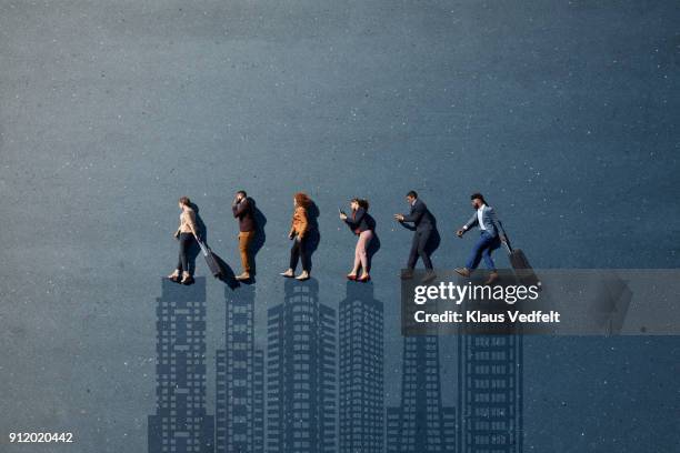 businesspeople laying in line, with suitcases and phones, on painted asphalt with skyline - building community concept stock pictures, royalty-free photos & images