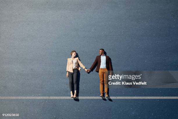 businesspeople lying down and holding hands, with line painted on asphalt - lying down stock pictures, royalty-free photos & images