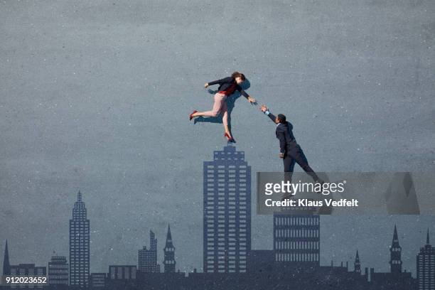 businesspeople reaching out for each other, while lying on asphalt painted as skyline - initiative photos et images de collection