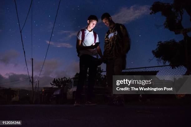 Alexander Cruz a senior at Escuela Superior Casiano Cepeda, stands in the dark near damaged electrical poles with his friend and schoolmate, Axel...