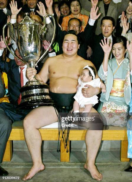 Surrounded by his supporters, Mongolian grand champion, or yokozuna, Asashoryu is all smiles as he holds his newborn daughter and the Emperor's Cup...