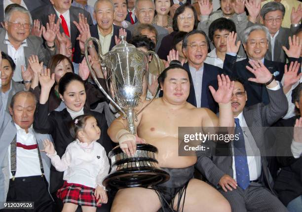 Accompanied by his wife and daughter , Mongolian grand champion Asashoryu shares a joy with his supporters as he holds the Emperor cup after the...