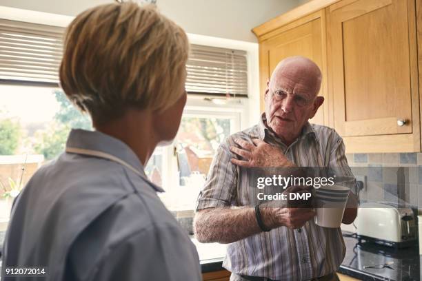 retired man with aching shoulder talking to home carer - arm pain stock pictures, royalty-free photos & images