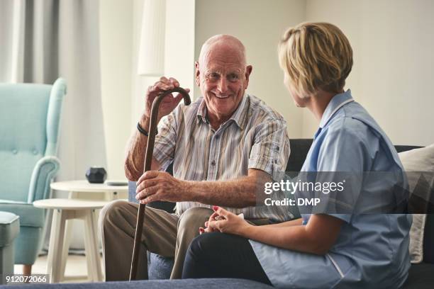 lächelnd zog mann mit weiblichen hause pflegeperson - elderly care stock-fotos und bilder