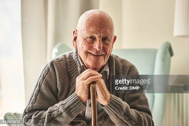 uomo anziano felice seduto a casa - terza età foto e immagini stock