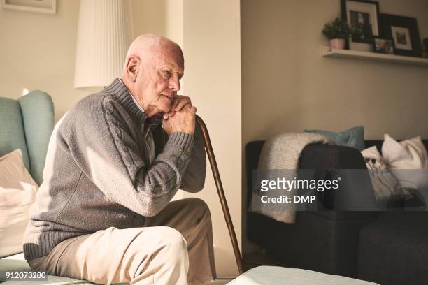 älterer mann sitzt allein zu hause - alter erwachsener stock-fotos und bilder