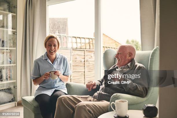 senior hombre y cuidador hembra disfrutando de café en casa - asistente sanitario fotografías e imágenes de stock