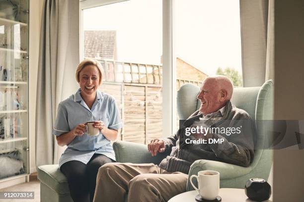 senior homme et femme soignant profitant de café à la maison - infirmière et maison photos et images de collection