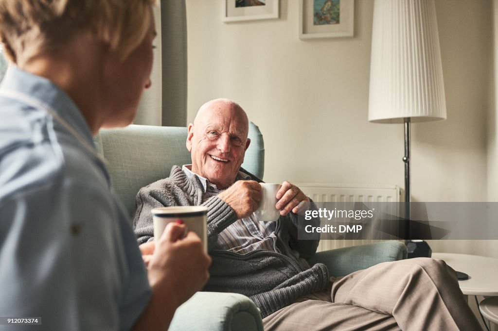 Smiling senior man talking to female caregiver