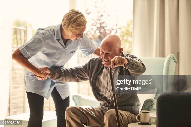 female healthcare worker supporting senior man at care home - chair stock pictures, royalty-free photos & images