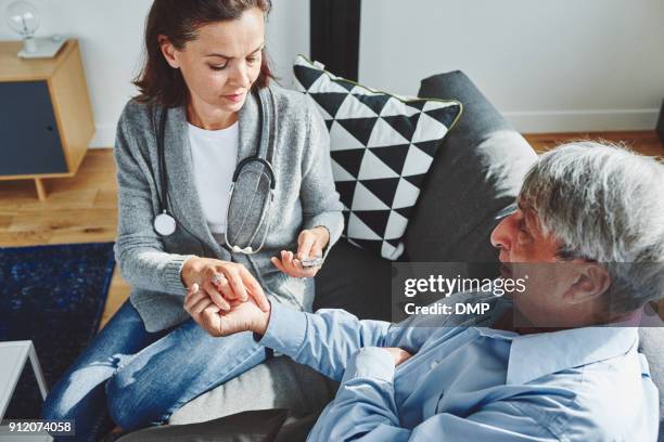 female doctor taking pulse of senior man - house call stock pictures, royalty-free photos & images