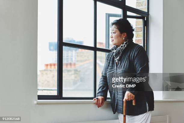 haute femme avec une canne à la recherche à l’extérieur de la fenêtre - walking stick photos et images de collection