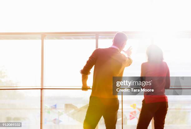 two people looking out window - gegenlicht stock-fotos und bilder
