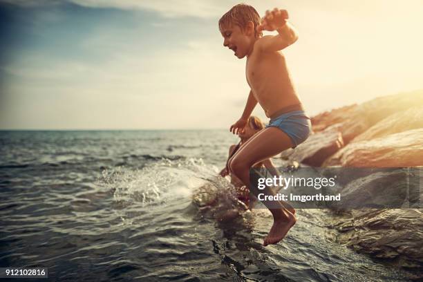 bruder und schwester von buhne ins meer springen - groyne stock-fotos und bilder