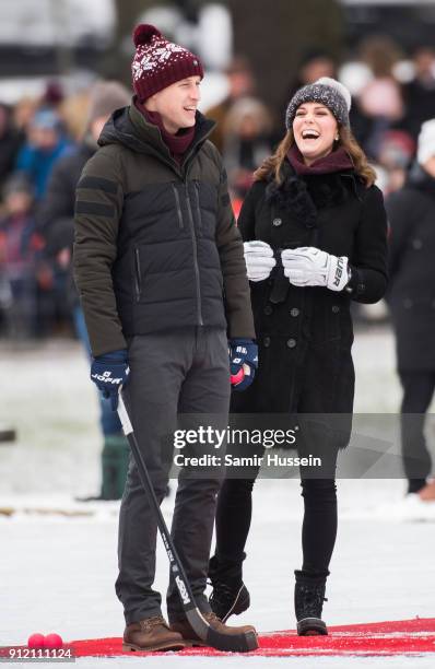 Catherine, Duchess of Cambridge and Prince William, Duke of Cambridge react after hitting the ball as they attend a Bandy hockey match where they...