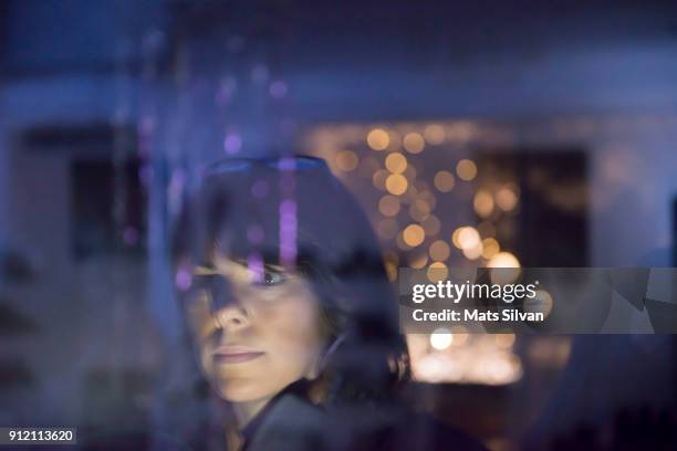 woman looking in a illuminated window store at night - schaufenster stock-fotos und bilder