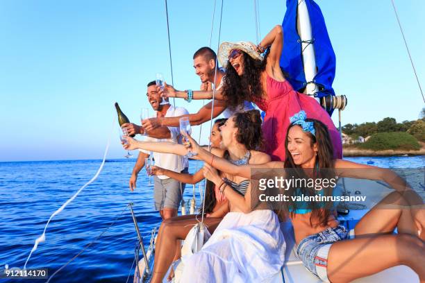 young people celebrating on yacht at sunset - shade sail stock pictures, royalty-free photos & images