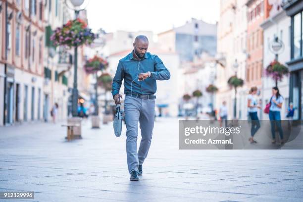 empresario comprobar el tiempo y caminando por la calle - puntualidad fotografías e imágenes de stock