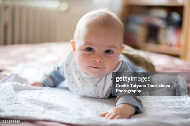 close portrait of little cute smiling baby boy at home, lying in bed - bébé garçon photos et images de collection