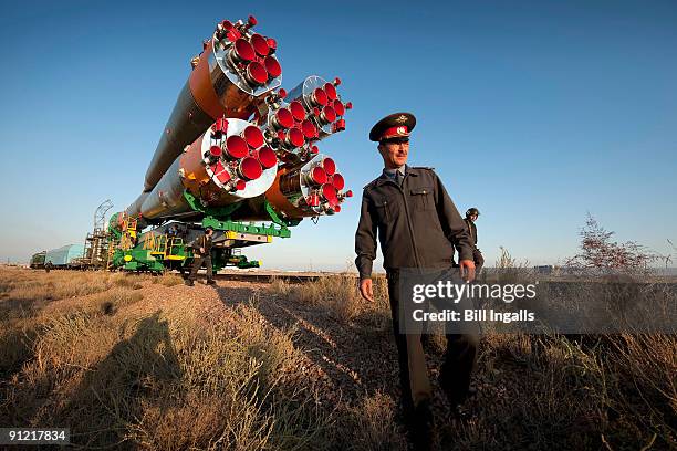 In this handout from NASA, Russian security officers walk along the railroad tracks as the Soyuz rocket is rolled out to the launch pad at the...