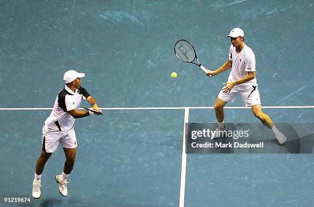 Jeff Coetzee watches as Rik De Voest of South Africa plays a volley in their doubles match with Marat Safin of Russia and Gilles Simon of France...