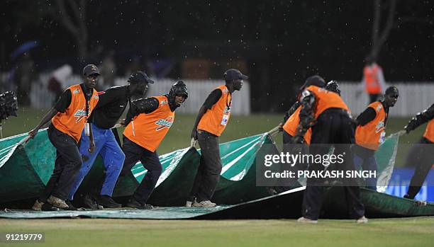 Ground staff cover the pitch as the ICC Champions Trophy match between India and Australia suspended due to rain at SuperSport Park in Centurion on...