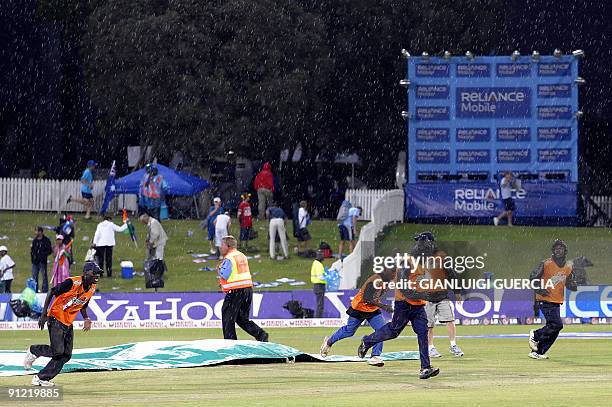 Pitch marshalls rush to cover the pitch as rain falls stopping the game between Australia and India on September 28, 2009 during the ICC Champions...