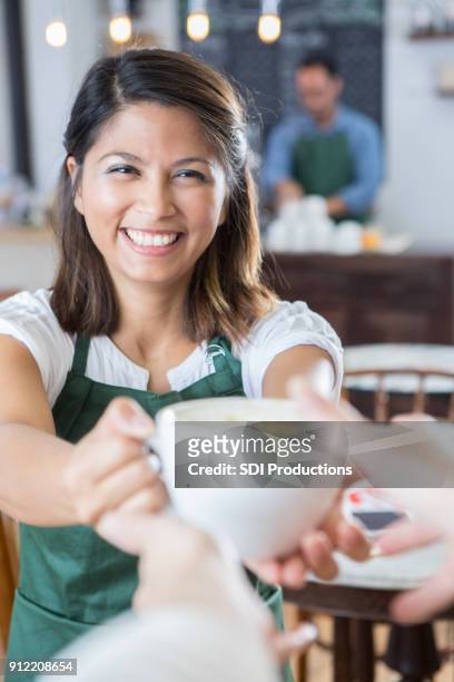 barista hands female customer a hot latte - hot filipina women stock pictures, royalty-free photos & images