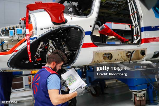 An employee inspects technical documents as he works on a AgustaWestland AW189 helicopter at a Leonardo SpA plant in Vergiate, Italy, on Tuesday,...