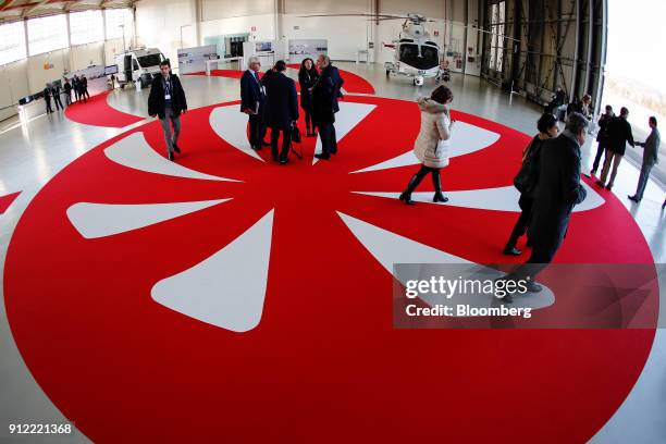 Attendees walk over the company logo during an investor day at a Leonardo SpA plant in Vergiate, Italy, on Tuesday, Jan. 30, 2018. Leonardo said it...
