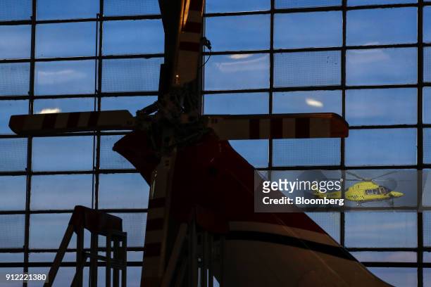 Helicopter flies past hangar windows during an investor day at a Leonardo SpA plant in Vergiate, Italy, on Tuesday, Jan. 30, 2018. Leonardo said it...