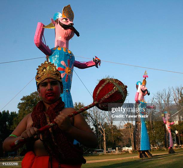 Kashmiri Pandit child in an attire of Hindu God stands in front the effigies of the demon king Ravana during the Dushera festival on September 28,...