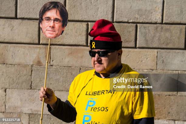 Man holds a cut-out mask of the former Catalan President, Carles Puigdemont as he takes part in a protest on January 30, 2018 in Barcelona, Spain....