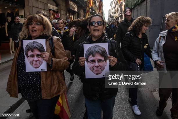 Women hold cut-out masks of the former Catalan President, Carles Puigdemont as they take part in a protest on January 30, 2018 in Barcelona, Spain....